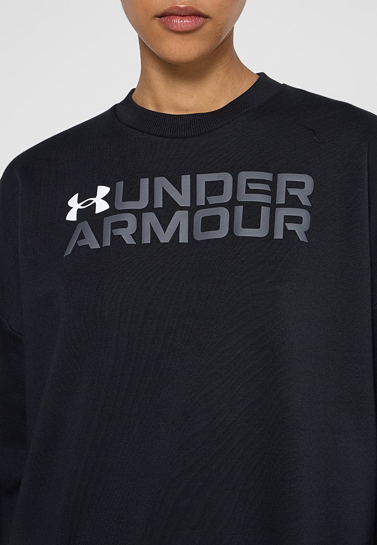 Eine Person trägt ein schwarzes Rundhals-Sweatshirt mit grauem "UNDER ARMOUR"-Text und dem weißen Under Armour-Logo auf der Brust.