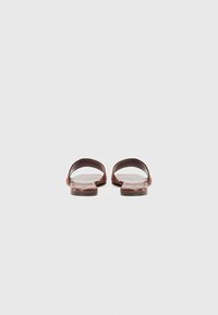Brune skinnsandal med åpen tådesign, med en glatt tekstur og en flat såle. Enkel, minimalistisk form uten dekorasjoner.