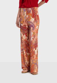 Pantalon à jambes larges avec un motif paisley aux teintes rouges vives, oranges et pourpres sur un fond crème ; fabriqué en tissu léger.