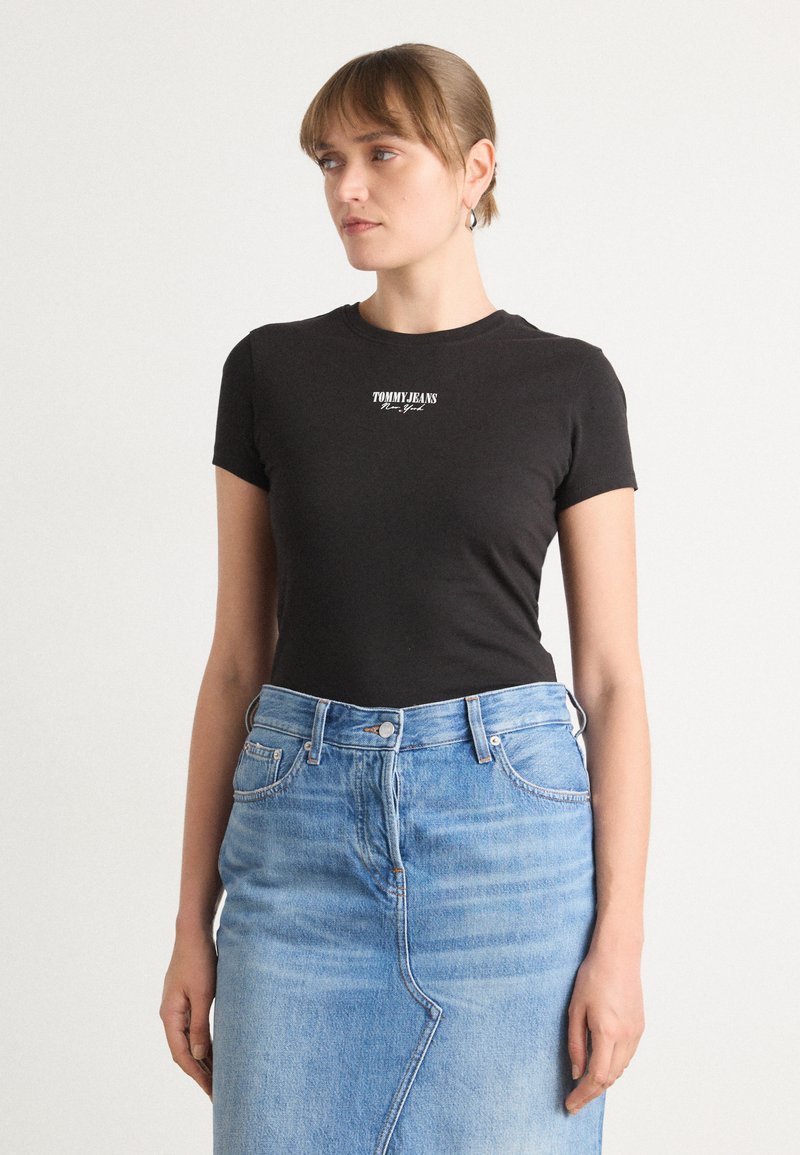 Czarna bawełniana koszulka z krótkim rękawem, z białym logo "TOMMY JEANS". W zestawie z jasnoniebieską dżinsową spódnicą z delikatnym detalem szwu.