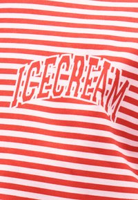 Ύφασμα με οριζόντιες ρίγες κόκκινου και άσπρου χρώματος, με τη λέξη "ICE CREAM" σε έντονα, παραμορφωμένα κόκκινα γράμματα στο κέντρο.