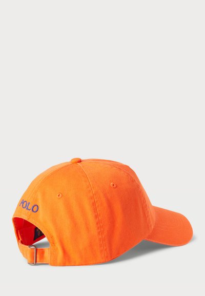 Oranžinė medvilninė beisbolo kepurė su išlenktu kraštu, violetiniu siuvinėjimu "POLO" logotipu ir reguliuojama juosta gale.