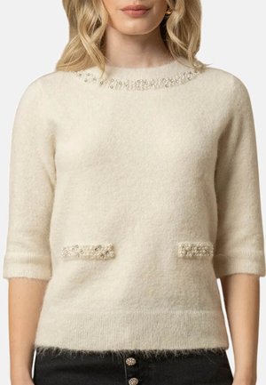 Maglione color crema realizzato in un materiale morbido e soffice. Presenta dettagli in perline sul colletto e due tasche frontali con decorazioni simili.