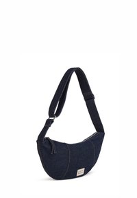 Sac épaule en denim bleu foncé avec sangle ajustable, fermeture éclair et petite étiquette de marque blanche à l'avant.