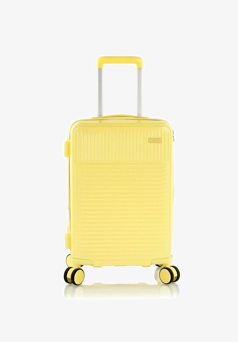 Valigia rigida gialla con design a coste, manico retrattile, quattro ruote doppie e chiusura a zip. Texture liscia e forma compatta.