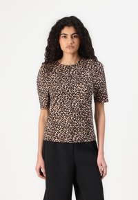 Beige ja must leopardi mustriga lühikeste varrukatega topp, millel on ümar kaelus ja pehme tekstuur. Kandes musti pükse.