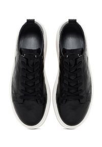 Black leather sneakers with a smooth texture, featuring a round toe, lace-up front, and white rubber sole. Minimal design with no visible patterns.