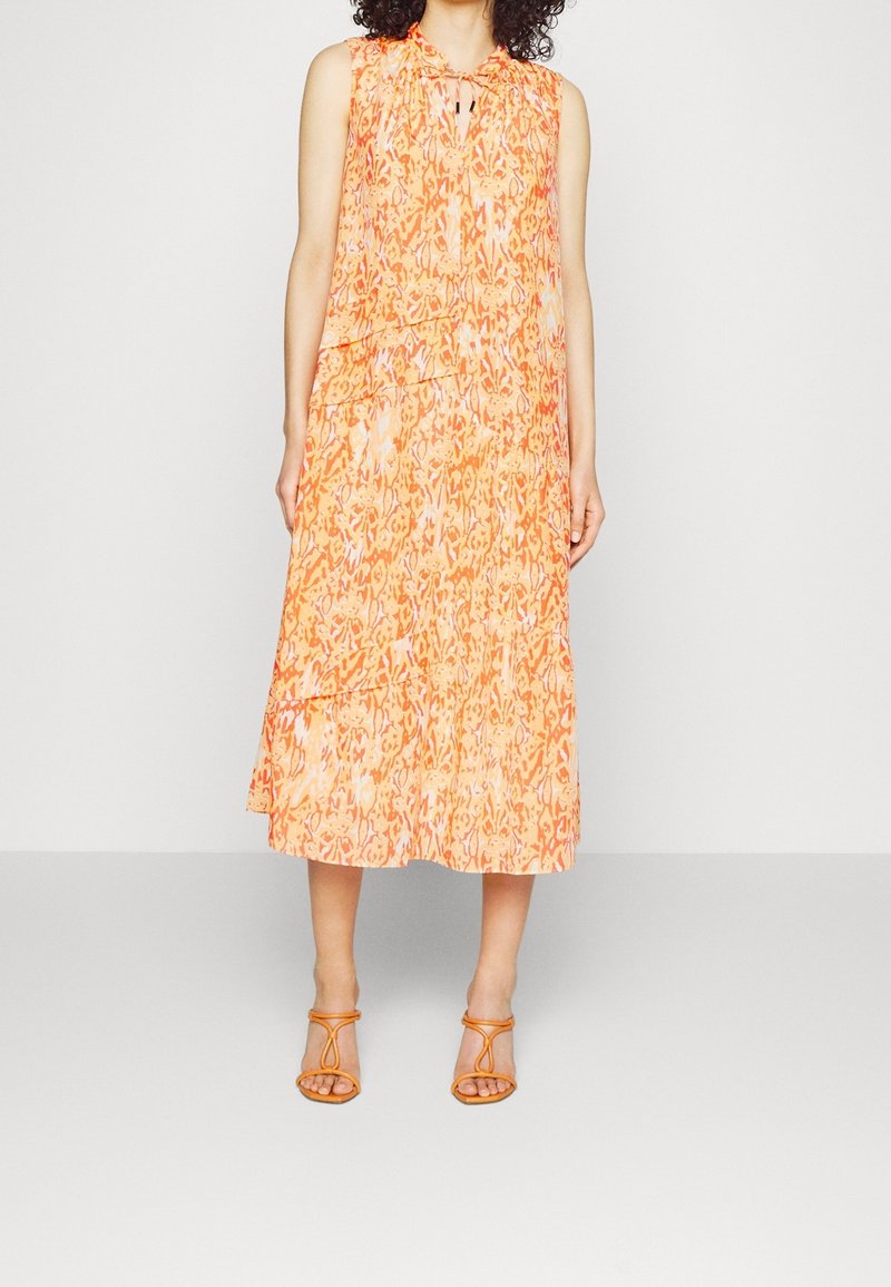 Ærmeløs orange midikjole med lagdelt design, prydet med et blomsterprint og en nøglehulshalsudskæring. Kombineret med orange sandaler med stropper.