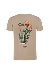 Beige t-shirt met een grote groene cactus en oranje bloemen graphic, tekst "Bel me als je verdwaald bent," en "PURE PATH" branding eronder.
