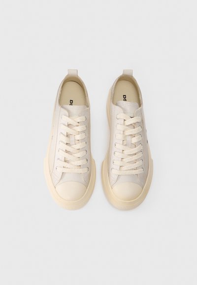 Zapatillas beige con parte superior de lona suave, puntera redonda y cordones crema. Cuenta con una lengüeta en el talón y suela texturizada.