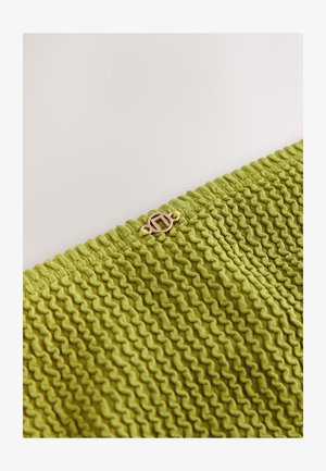 Țesătură verde texturată cu un model unduit, având un detaliu cu închizătoare de culoare aurie. Materialul pare tricotat și se întinde ușor.