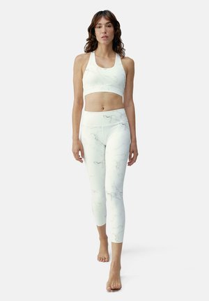 Ensemble de sport blanc comprenant un crop top et un legging avec un motif marbré. Texture lisse et ajustement serré, conçu pour le confort et la flexibilité.