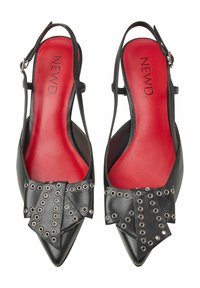 Czarne skórzane buty na obcasie typu slingback z wysmuklonym noskiem, ozdobione dużą kokardą z metalowymi nitami w kolorze srebrnym oraz jaskrawoczerwonym wkładem.