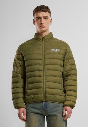 Olivenfarvet pufferjakke med lodret syninger, høj krave og lynlås lukning. Har et logo-patch på venstre bryst og lange ærmer.