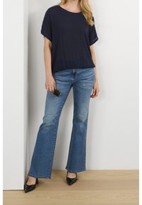 Haut à manches courtes bleu marine associé à un jean évasé bleu clair. La tenue est complétée par des escarpins noirs à bout pointu. Design simple et décontracté.