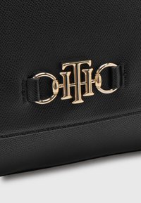 Borsa a tracolla in pelle nera con texture, con hardware in tonalità oro e accenti metallici. Il design include un dettaglio distintivo con fibbia.