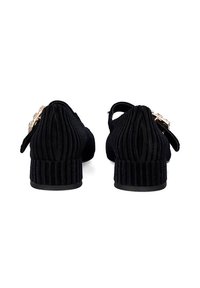 Zapatos de tela negra con textura estriada, parte trasera redondeada y un tacón bajo. Presentan un acento de hebilla contrastante para el cierre.