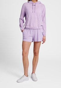 Hellblauer Hoodie mit Kordelzug, Vordertasche und passenden Shorts aus weichem Material, kombiniert mit weißen Sneakers.