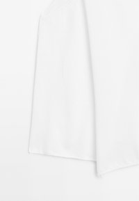 Witte stoffen top met een losse, cropped ontwerp en een zachte textuur met eenvoudige randen, geschikt voor casual gebruik.