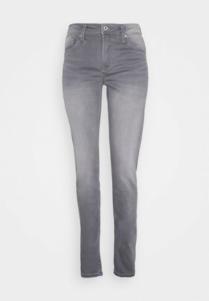 Strakke grijze jeans met knopen en rits aan de voorkant, vijf zakken en lussen voor een riem, weergegeven tegen een effen witte achtergrond.