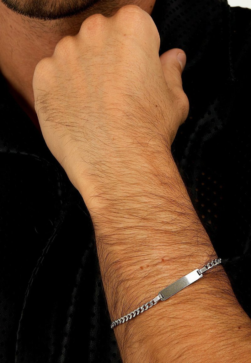 Silberne Kettenarmband mit einem flachen rechteckigen Anhänger und verknüpftem Design. Verfügt über eine polierte Oberfläche und eine strukturierten Fläche auf dem Anhänger.
