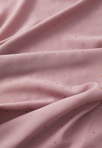 Rosa stof med en blød tekstur, der har små guld-sequin prikker spredt over det hele. Materialet fremstår let og glat.