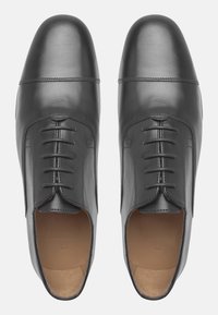 Schwarze Lederschuhe mit glatter Oberfläche, Schnürdesign, spitzer Zehenform und minimalen Nähdetails. Braune Einlegesohlen sichtbar.