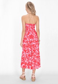 Rochie maxi fără bretele, cu imprimeu floral în nuanțe de roz și roșu. Prezintă un corset din material plisat, fustă fluidă și țesătură ușoară. Purtați cu sandale cu talpă înaltă și curea.