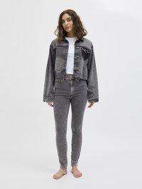 Γκρίζο τζην cropped μπουφάν με κουμπιά μπροστά και χαλαρή εφαρμογή, συνδυασμένο με γκρίζες ψηλό μεσάτες skinny τζιν, και τα δύο σε ξεθωριασμένο φινίρισμα.