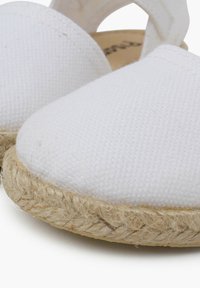 Baltos drobės espadrilės be užsegimų su tekstūruota paviršiumi ir jūrinio pluošto padu. Apvalus pirštas ir išpjova kulne geresniam oro pralaidumui.