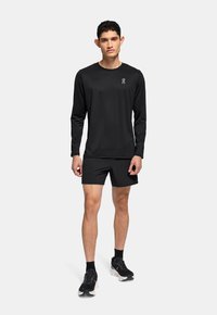 Sorte langærmede skjorte og shorts sæt, lavet af letvægtsstof. Har et logo på brystet og shorts, der går til knæene. Sorte træningssko.