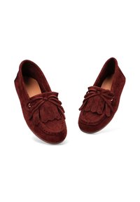 Par de mocasines de ante de color rojo oscuro con detalle de flecos y un lazo en la parte superior, ligeramente inclinados hacia afuera sobre un fondo blanco.