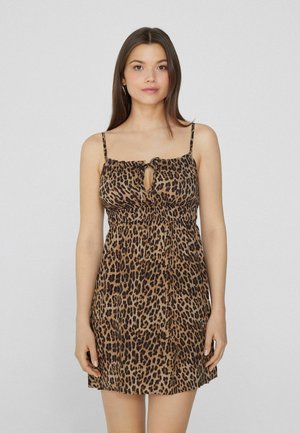 Robe imprimée léopard avec bretelles spaghetti réglables, décolleté en forme de clé à l'avant, taille cintrée et jupe fluide. Couleurs marron et noir.
