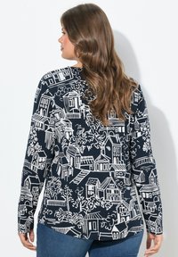 Langärmliges Oberteil in Marineblau mit einem weißen Druck von Häusern und Bäumen. Weicher Stoff mit lockerem Schnitt und abgerundetem Saum.