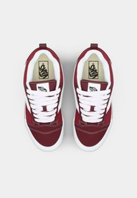 Crvene platnene tenisice s bijelim vezicama i bočnim prugama, s podstavljenim ovratnikom i teksturiranom gumenom potplatom, označene Vans logotipom.