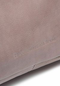 Accessorio in pelle di un morbido taupe con superficie texturizzata. Presenta il logo impresso "The Chesterfield Brand" e un sottile dettaglio di cucitura.