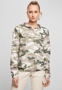 Roheliste, beežide ja valgete toonidega kamuflaažmustriline pulloverjakk; ees tasku, tõmblukk ning elastsed mansetid ja ääred.