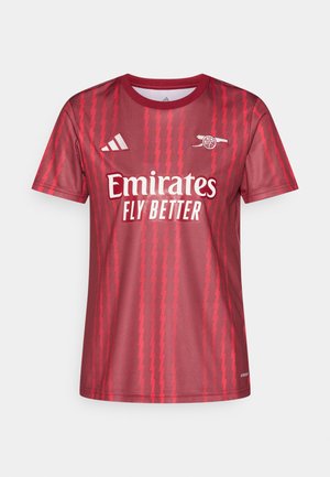 Červený sportovní dres s krátkým rukávem, zdobený cikcak vzory, bílým logem "Emirates Fly Better" a logem Adidas na hrudi. Hladká textura látky.