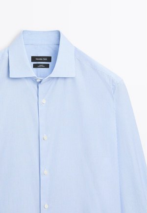 Camicia a maniche lunghe a righe blu chiaro, con chiusura frontale a bottoni, in tessuto morbido, colletto classico, dotata di cinque bottoni bianchi e un'etichetta cucita all'interno del colletto.