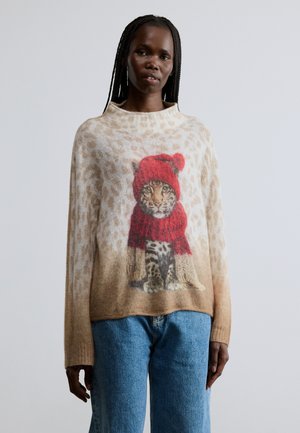 Béžový svetr s grafikou leoparda, který má na sobě červený klobouk a šálu. Pozadí má vzor leoparda. Volný střih, měkká textura.