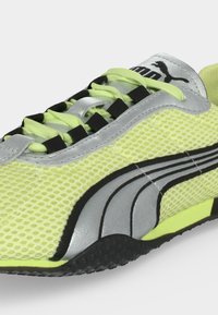 Baskets en mesh jaune avec logo Puma noir et argenté, lacets jaune néon et semelle noire texturée.