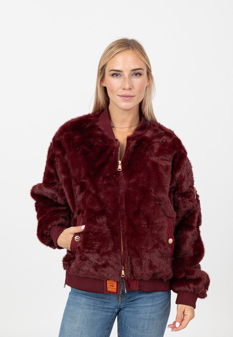Giacca bomber in pelliccia sintetica bordeaux con zip frontale, polsini a coste e tasche laterali. Presenta un'etichetta con logo in tessuto all'orlo.