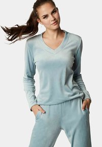 Lichtblauw velours loungepak bestaande uit een langemouwen top met een V-hals en bijpassende broek met zijzakken. Zachte textuur.
