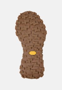 Suola in gomma marrone con un motivo a rilievo e tasselli per una migliore trazione. Presenta un emblema giallo Vibram e il numero "38" impresso.