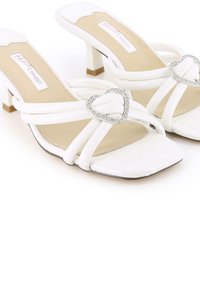 Sandalias abiertas de toe blanco con una punta cuadrada, que cuentan con múltiples correas y un acento de strass en forma de corazón. Diseño de tacón bajo.