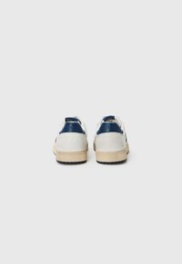 Hvite lær sneakers med marineblå detaljer, teksturert overflate og en beige gummisåle. Har preget merkevare på hælen og et glattes design.
