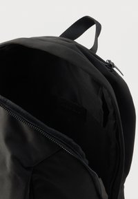 Μαύρο σακίδιο πλάτης με λείο εξωτερικό, κλείσιμο με φερμουάρ και εσωτερική ετικέτα. Το εσωτερικό είναι επενδεδυμένο με απαλή και υφή υφασμάτινη φόδρα.