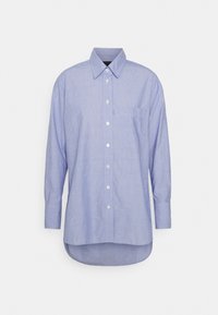 Light blue button-up shirt made of textured cotton, featuring long sleeves and a chest pocket, with a curved hem at the bottom.