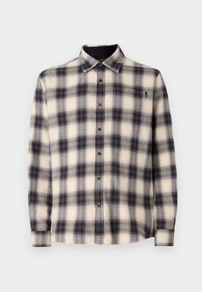 Kreemjas, mustas ja hallis pliidiga särk. Omab pikaid varrukaid, laia kraed ning esi-nuppe koos väikese rinnataskuga.