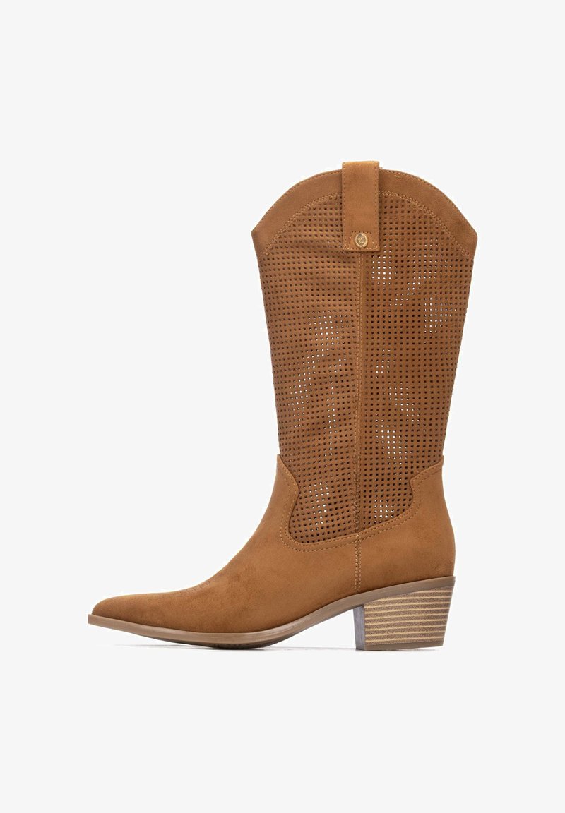 Bota vaquera de ante marrón con diseño perforado, punta puntiaguda y tacón apilado. Cuenta con una presilla en la parte superior y un acabado liso y texturizado.